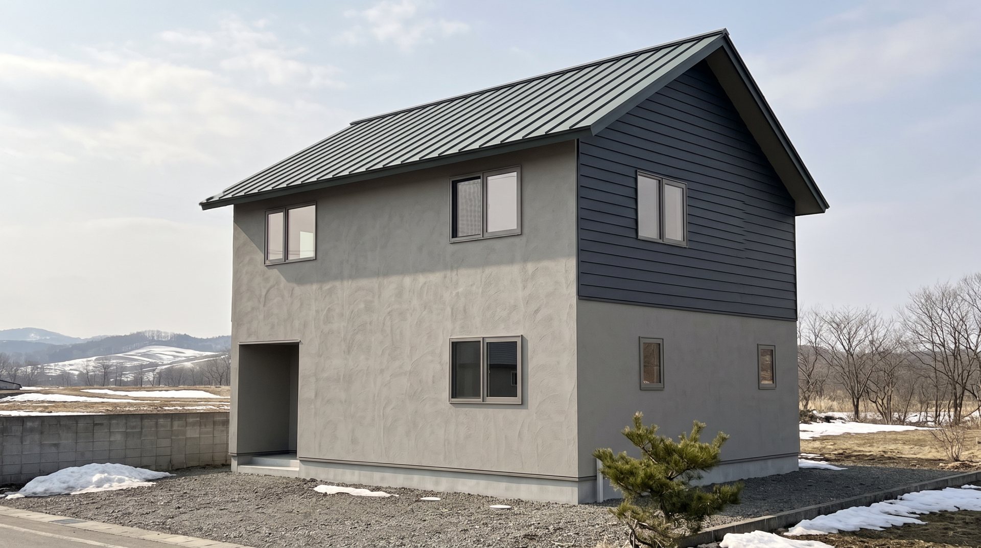 コテの模様が出た塗り壁と横張りの板の外壁の、2階建ての住宅。遠くに雪の残る低い山並み（AIで作った見本の画像）